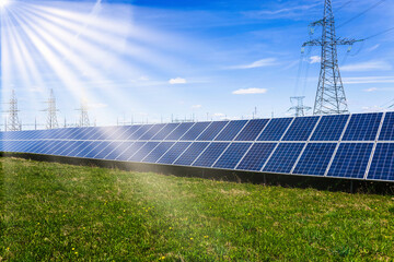 Solar panels, high voltage electricity towers, and sun rays