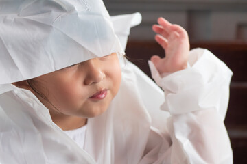 Naklejka premium Unhappy little girl having trouble while wearing raincoat in rainy monsoon season