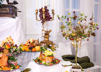 Buffet table with meat snacks, baked pigs in dough, cheese, turkey with fruit, decorated with candelabra and gramophone
