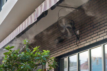 Water mist machine creates coolness on sunny day for comfort of visitors during heat and high...