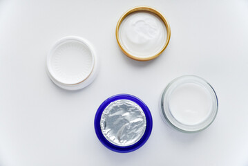 A jar of face cream on a white background. Night cream and hand close-up.