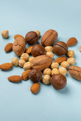 Various nuts scattered on a light background. Almonds, hazelnuts, pecans, macadamia in a pile close...