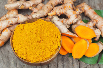 Turmeric powder and fresh turmeric on old wooden table background
