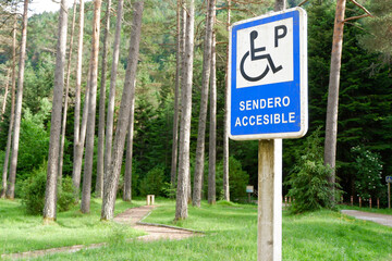 Road sign for accessible parking in the forest outside in Bielsa, Huesca, Spain. Text on the sign...