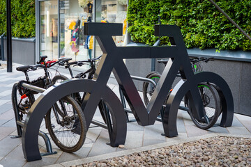 Interesting bike rack stand in shape of large bicycle with numerous bikes parked at it in urban...