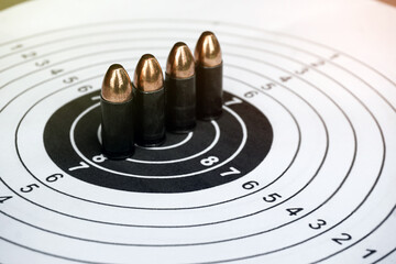 Fototapeta na wymiar 9mm black bullets on circle shooting target paper, soft and selective focus on bullet.