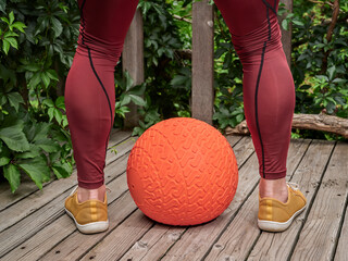 male in compression pants is exercising with a heavy slam ball on a backyard deck, functional fitness and backyard gym concept