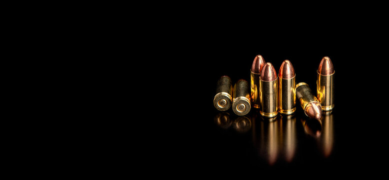 Pistol cartridges 9 mm on a smooth glossy surface with reflections. Ammunition for pistols and PCC carbines on a dark back.