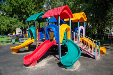 Slides made of red yellow blue plastic on the playground on a bright sunny day. Playgrounds, sports, health entertainment.