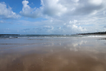 Reflections of the cloudy sky in the water on the beach. Deserted paradise beach.