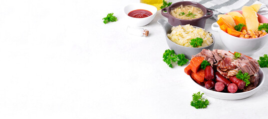 Web banner with Cocido Madrileno, traditional Spanish stew with assorted meat, vegetables, chickpea and noodles served separately on white. Mockup with copy space