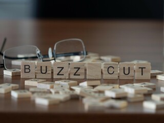 buzz cut word or concept represented by wooden letter tiles on a wooden table with glasses and a...