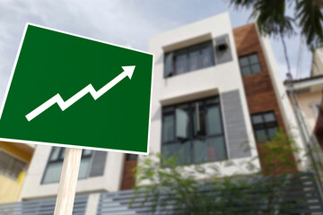 A sign showing an upward arrow in front of an apartment building. Concept of increasing home prices and value or a real estate boom.