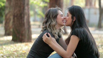 Lesbian couple kissing each other outdoors at the park LGBT women