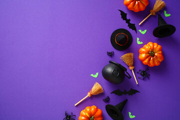 Happy Halloween holiday concept. Halloween decorations, pumpkins, bats, witch brooms and hats on purple background. Flat lay, top view, overhead