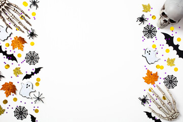 Happy Halloween holiday concept. Halloween double border banner design. Flat lay, top view Halloween decorations, bats, spiders, webs, skeleton hands, ghosts on white table.