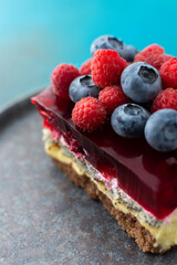 A piece of cake with poppy seeds and berry jelly, cake on a plate decorated with juicy raspberries and blueberries