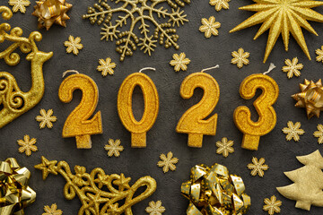 Merry Christmas and Happy New Year 2023, 2023 cake candles and various holiday decorative ornaments in gold color on gray background