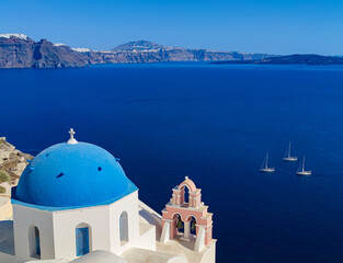 Fototapeta na wymiar photography of point view from OIA village in santorini island, greece to the caldera volcano with some boats and blue and white churches