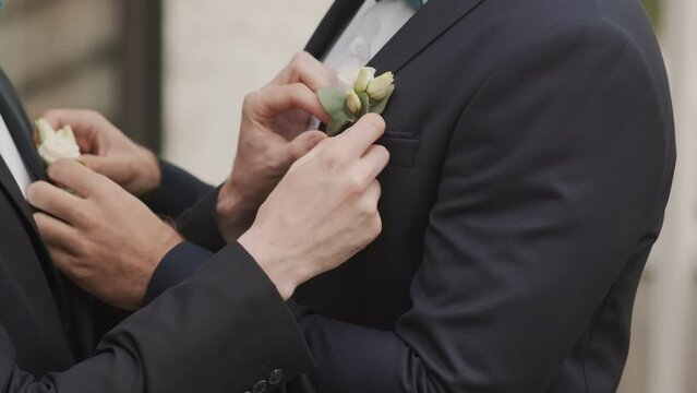 Midsection slowmo of two unrecognizable grooms adjusting their tuxedos while preparing for wedding ceremony for two beloved gay men