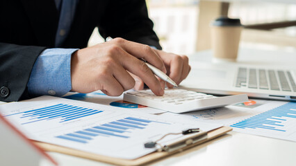 An accountant, businessman or financial professional presses calculators, computes, analyzes graphs, business reports, and financial charts at the office. economic concepts, finance, market research