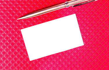 Blank business card and golden pen on burgundy background. A rectangle of white paper and a...