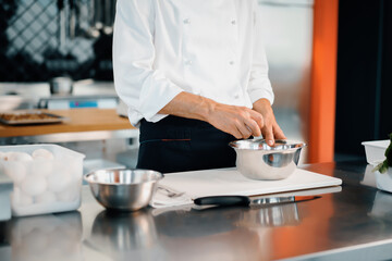 Fototapeta na wymiar Restaurant professional kitchen: chef prepares a delicious dish, beats eggs in a bowl