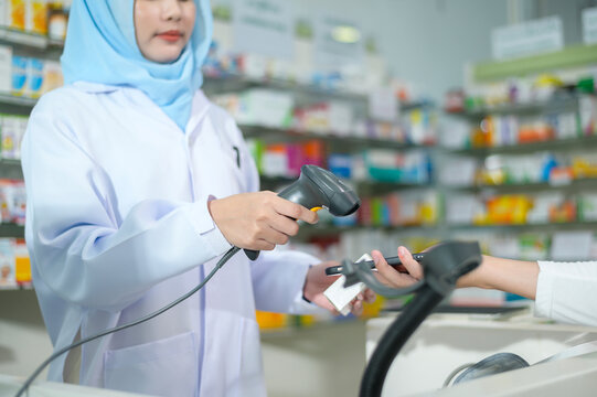Female muslim pharmacist scanning barcode in a modern pharmacy drugstore.