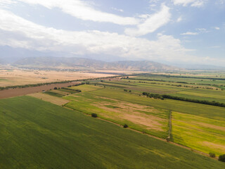 Fototapeta na wymiar Fantastic landscape, aerial photography from a drone of farmers' fields against the background of mountains. Farm lands and fields are not far from Almaty.