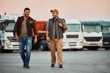 Happy truck drivers talk while walking on parking lot.