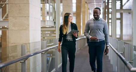 Business colleagues discuss sales strategy and use a tablet while walking in the office. Corporate employees planning marketing strategy with an online social media platform in a startup - Powered by Adobe