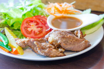 Pork steak in a plate with green peas and tomatoes