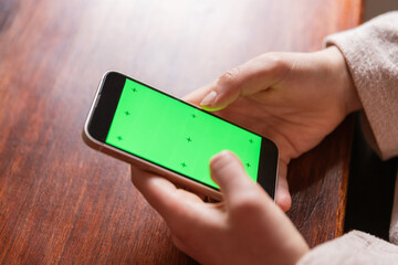 Anonymous woman browsing smartphone with green screen