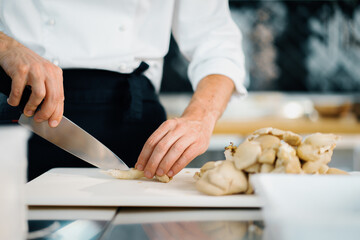 Professional kitchen: two chefs prepare food. The cook cuts mushrooms to prepare a delicious dish.