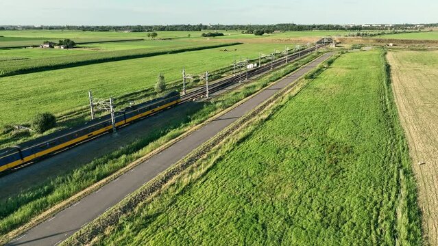 Intercity train passing on a railroad track in the country side at the end of the day seen from above.