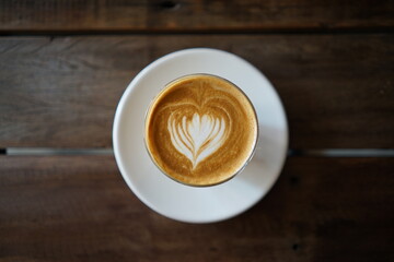 A cup of cafe latter with latte art in white cup with wooden table background
