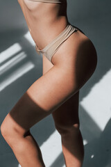 Sunlight through the windows. Woman in underwear with slim body type is posing in the studio