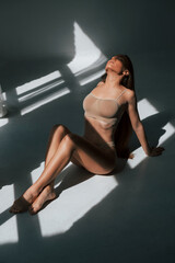Enjoying sunlight. Woman in underwear with slim body type is posing in the studio