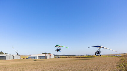 Fototapeta na wymiar Microlight Light Aircraft's Flying Two Take Off Grass Airfield Runway Blue Sky Adventure 