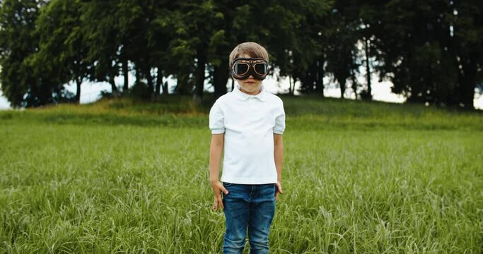 child boy pilot with glasses looking to the sky, playing outdoors. Fantasy and imagination of the child. High quality 4k footage