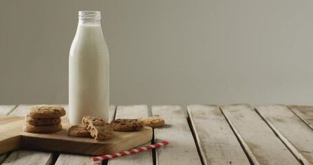 Video of glass bottles of milk and cookies on wooden table on white background - Powered by Adobe