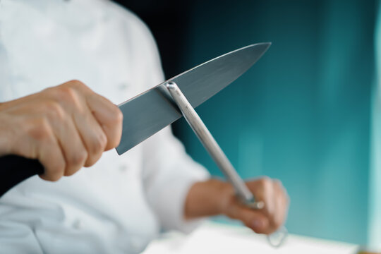 Professional restaurant kitchen, male chef sharpening a knife