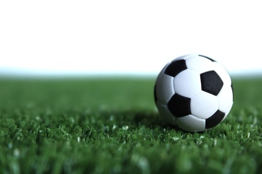 Selective focus image of football, soccer ball on green soccer field isolated on white background