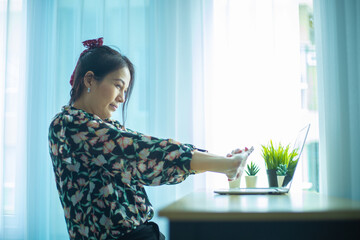 Asian woman is relaxing to stretching while break time after working hard at home