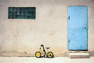 Children's bicycle against the wall of the house next to the door and window