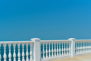 Summer view with classic white balustrade and empty terrace overlooking the mediterranean sea, vacation idea. Free space for text