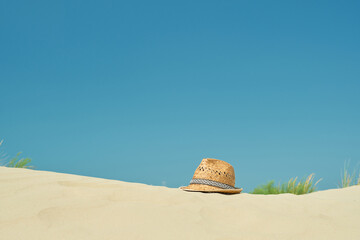 Fototapeta na wymiar Straw hat on the sand on the beach against the blue summer sky, close-up, copy space for text. A beautiful sunny day. Vacation, summer concept