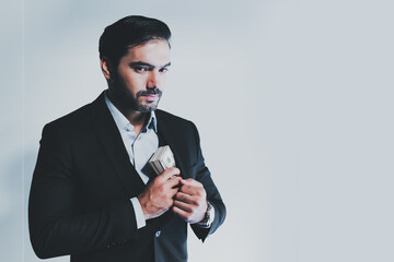 Portrait of Caucasian businessman in suit hides Dollars. Cheerful manager holding dollar banknotes, rejoicing successful profitable deal. man hides or takes wad of money from his pocket.