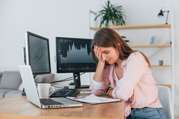 Obraz premium Conception of failure. Female stock broker in casual clothes is working in the office by pc