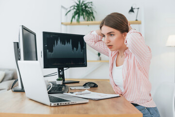 Shocked look. Female stock broker in casual clothes is working in the office by pc